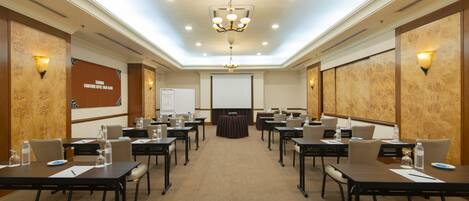 A conference room with multiple tables, chairs, and a projector screen.
