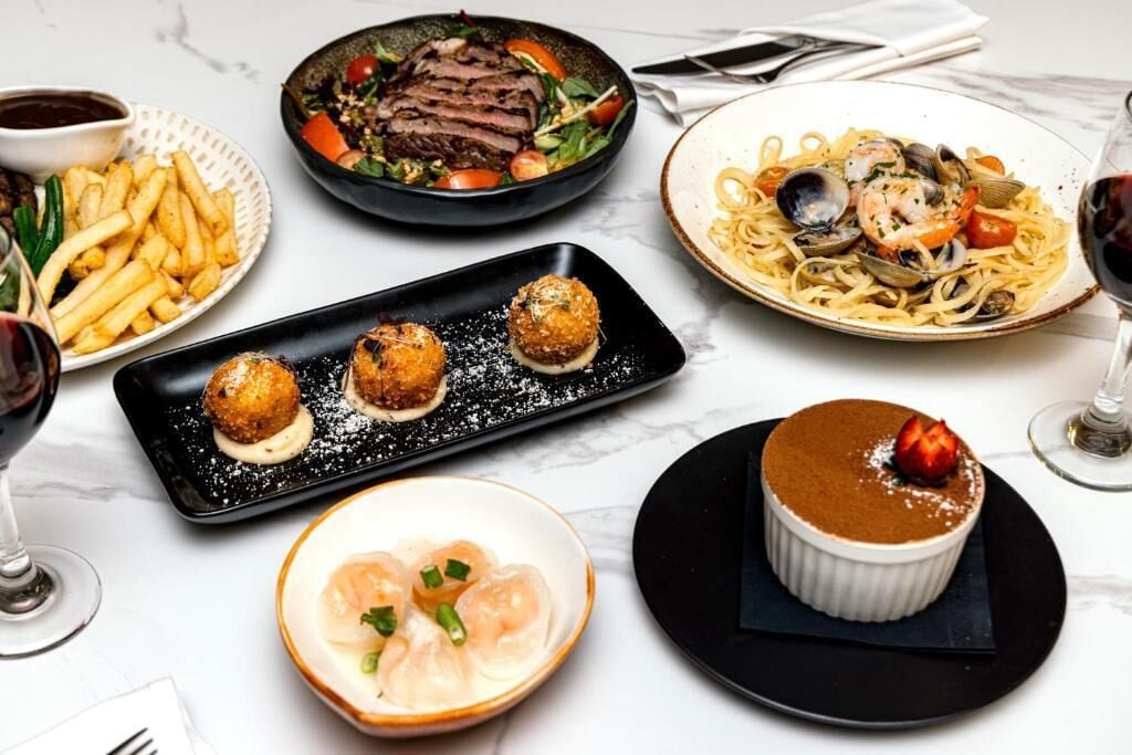 Variedad de platos, incluyendo filete, pasta y camarones, que sugieren una experiencia gastronómica de alta cocina.