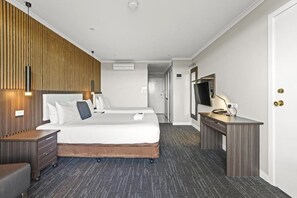 Een hotelkamer met twee bedden, een bureau, een televisie en een kledingkast.