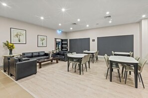Ein modernes Hotelzimmer mit einer Couch, einem Esstisch, Stühlen und Kunstwerken an den Wänden.