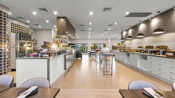 A modern restaurant interior with a central bar, seating area, and kitchen.