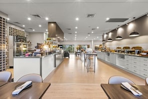 Un restaurant moderne avec un bar central, un espace salon et une cuisine.