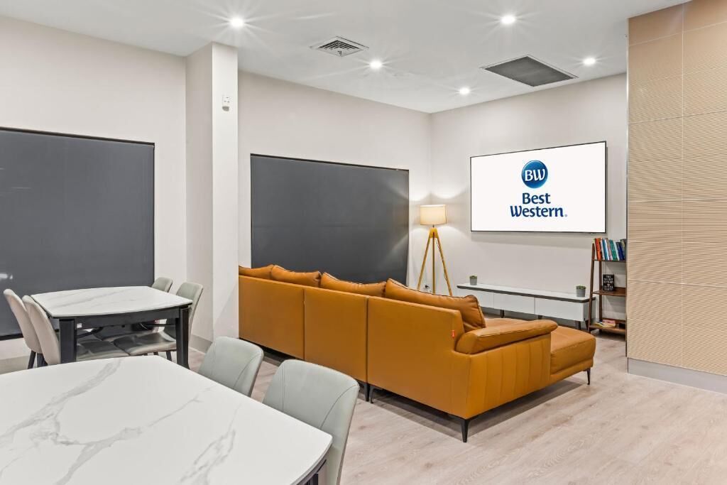 A conference room with a large table, a sofa, a projector screen, and a sign reading 'Best Western.'