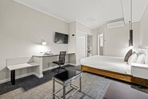 Une chambre d’hôtel équipée d’un lit, d’un bureau, d’une chaise, d’une télévision et d’une machine à café.