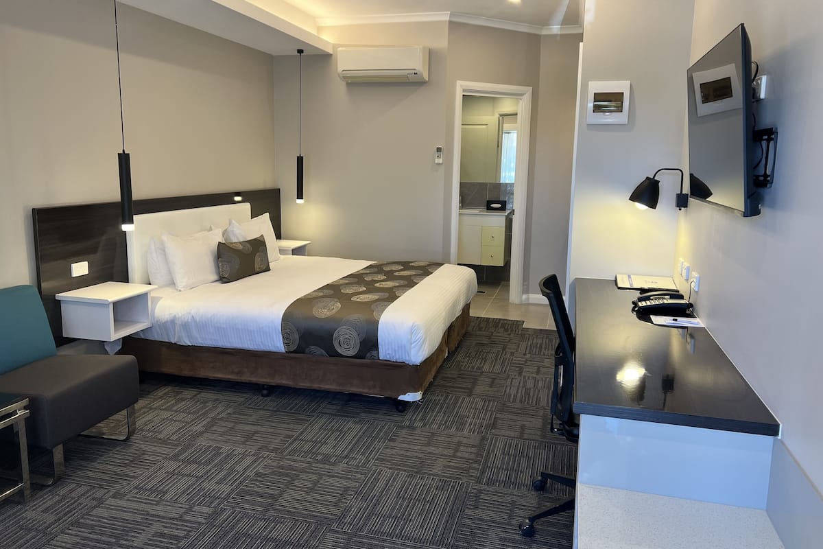 Una habitación de hotel moderna con una cama grande, mesitas de noche, un escritorio y una silla.