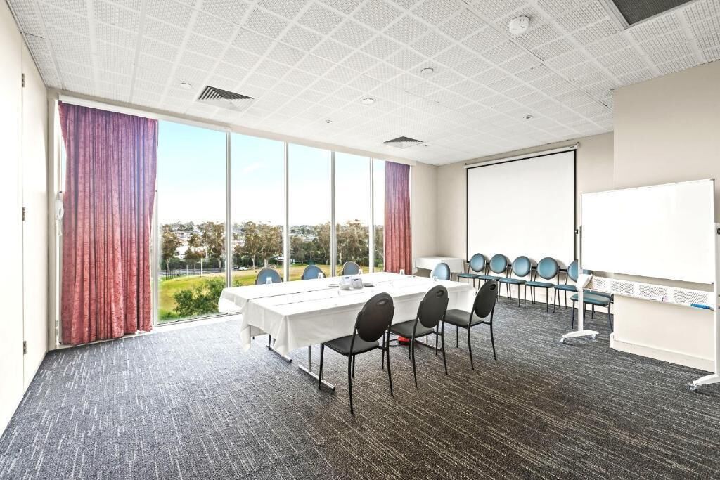 A conference room with a large table, chairs, a whiteboard, and a view of the outdoors.