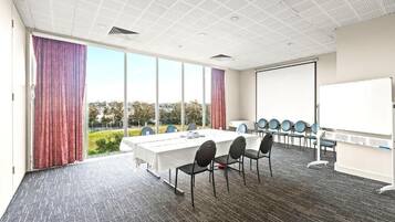 A conference room with a large table, chairs, a whiteboard, and a view of the outdoors.