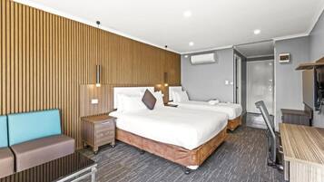 A hotel room with two beds, a sofa, a desk, and a wardrobe.
