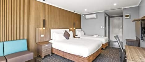 Une chambre d’hôtel avec deux lits, un canapé, un bureau et une armoire.