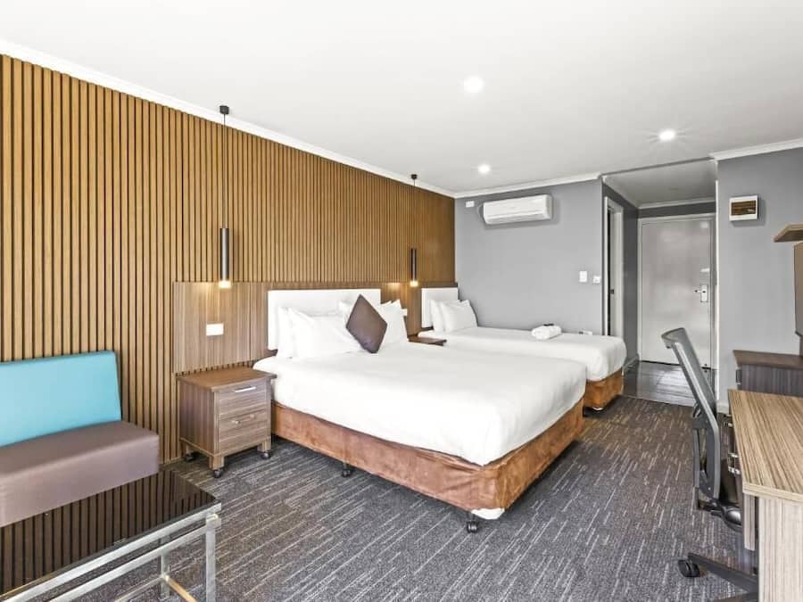 A hotel room with two beds, a sofa, a desk, and a wardrobe.