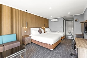Une chambre d’hôtel avec deux lits, un canapé, un bureau et une armoire.