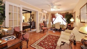 A spacious living room with a ceiling fan, a red and white patterned rug, and a piano. - Sabal Palm House Bed & Breakfast (Lake Worth)