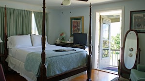 A four-poster bed with a ceiling fan, a television on a stand, and a door leading to a balcony. - Sabal Palm House Bed & Breakfast (Lake Worth)