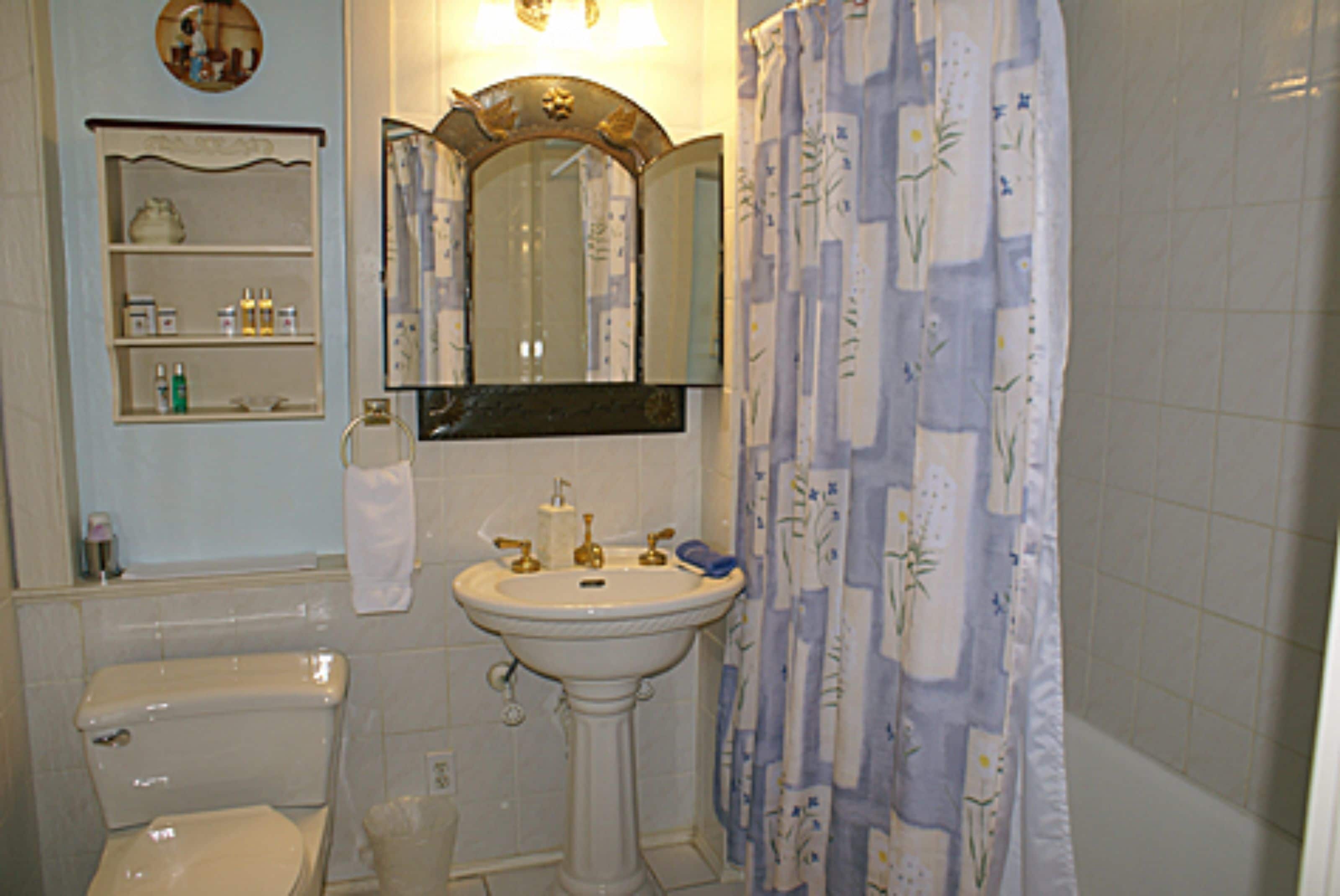 Et badeværelse med toilet, håndvask og spejl.