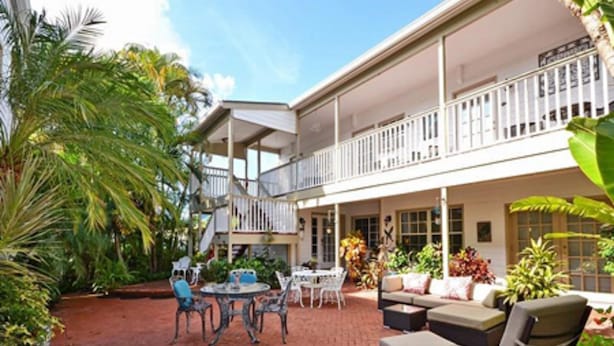 A two-story building with a covered patio area featuring outdoor seating and a staircase leading to the upper level. - Sabal Palm House Bed & Breakfast (Lake Worth)