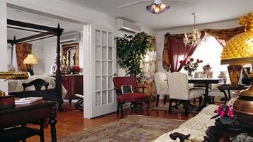 A traditional room with a four-poster bed, a chandelier, and a large window with curtains.