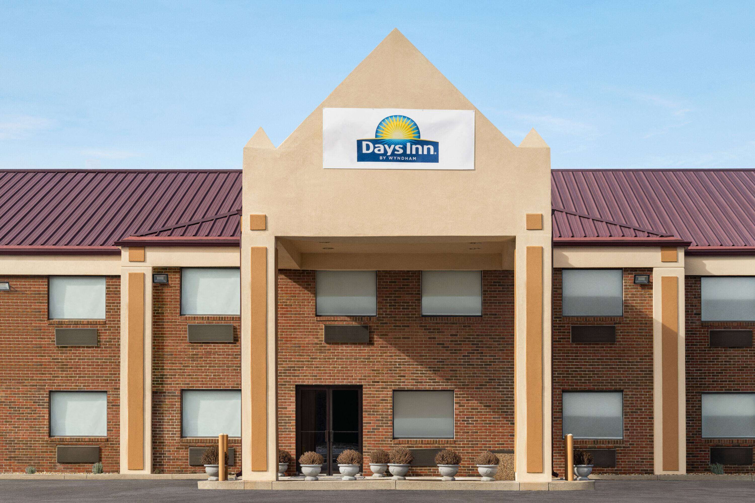 A Days Inn by Wyndham hotel with a prominent sign, brick facade, and a symmetrical entrance.