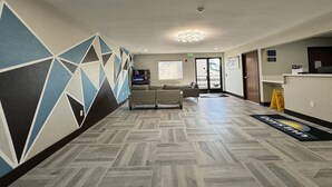 Un vestíbul d'hotel amb un disseny de paret geomètric, una taula de recepció, un sofà i un paviment estampat.