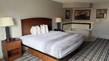 A hotel room with a bed, two bedside lamps, a nightstand, a digital clock, a bedside table, a large window, a bathroom with a bathtub, and a towel rack.