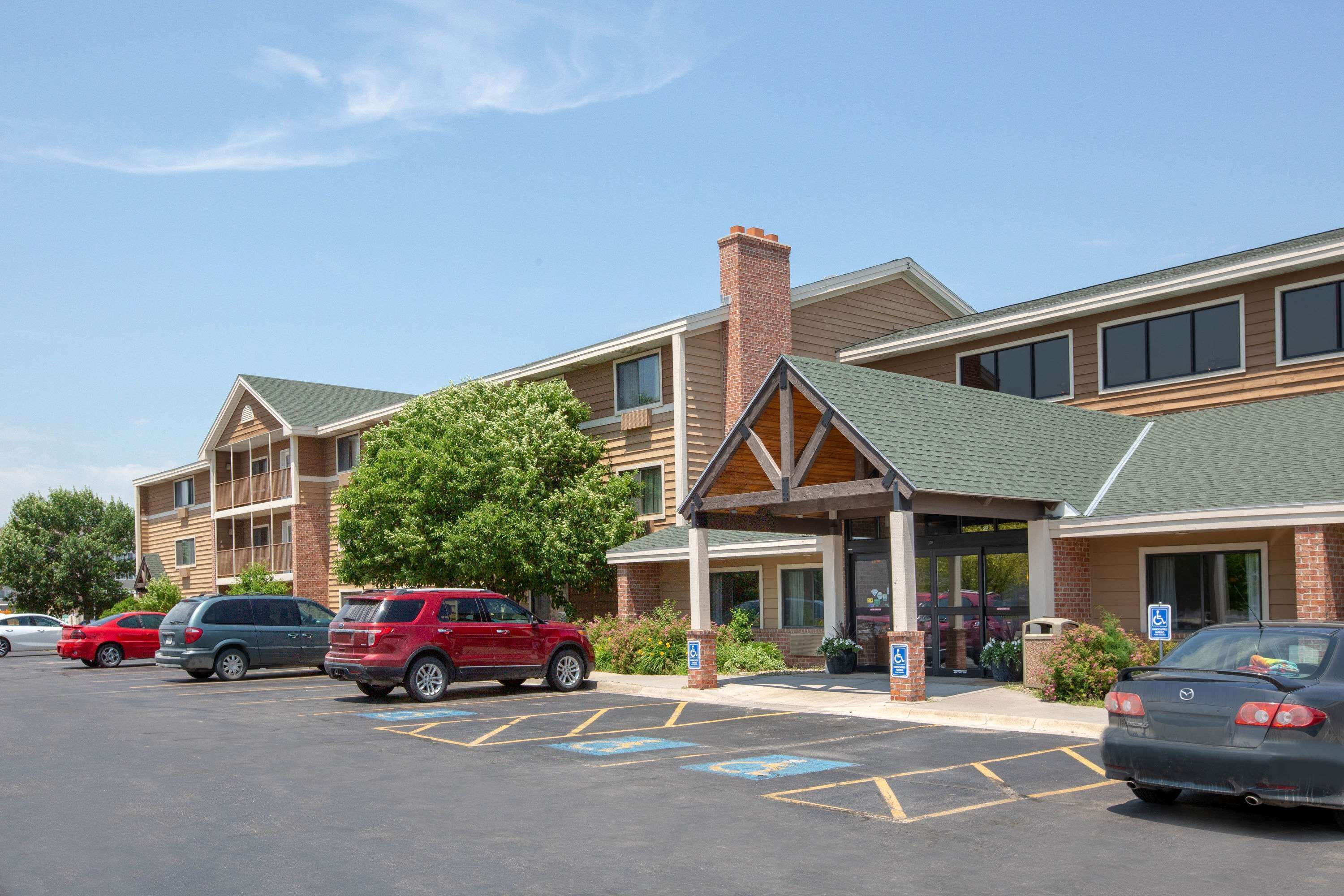 A hotel with a brick facade, multiple parking spaces, and a covered entrance.