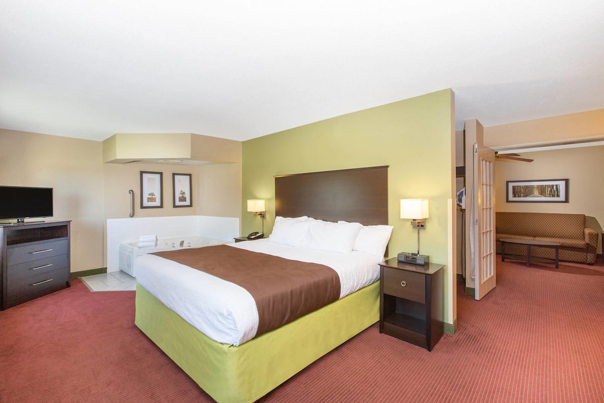 A hotel room with a bed, bedside tables, a TV, a desk, and a chair.