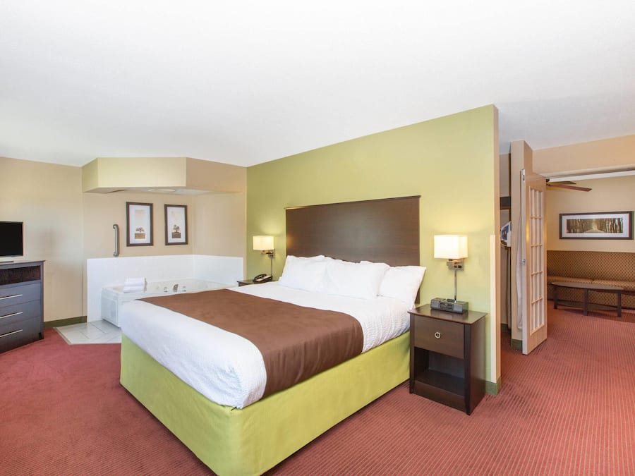 A hotel room with a bed, bedside tables, a TV, a desk, and a chair.
