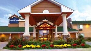 A hotel with a covered entrance, a sign for 'Amerind Inn by Wyndham,' and a landscaped garden with colorful flowers.