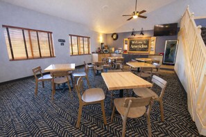 Une chambre d’hôtel avec plusieurs tables et chaises, un ventilateur de plafond, une horloge et une pancarte de bienvenue.