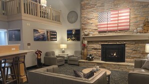 A hotel lobby with a stone fireplace, American flag, and a clock on the wall.