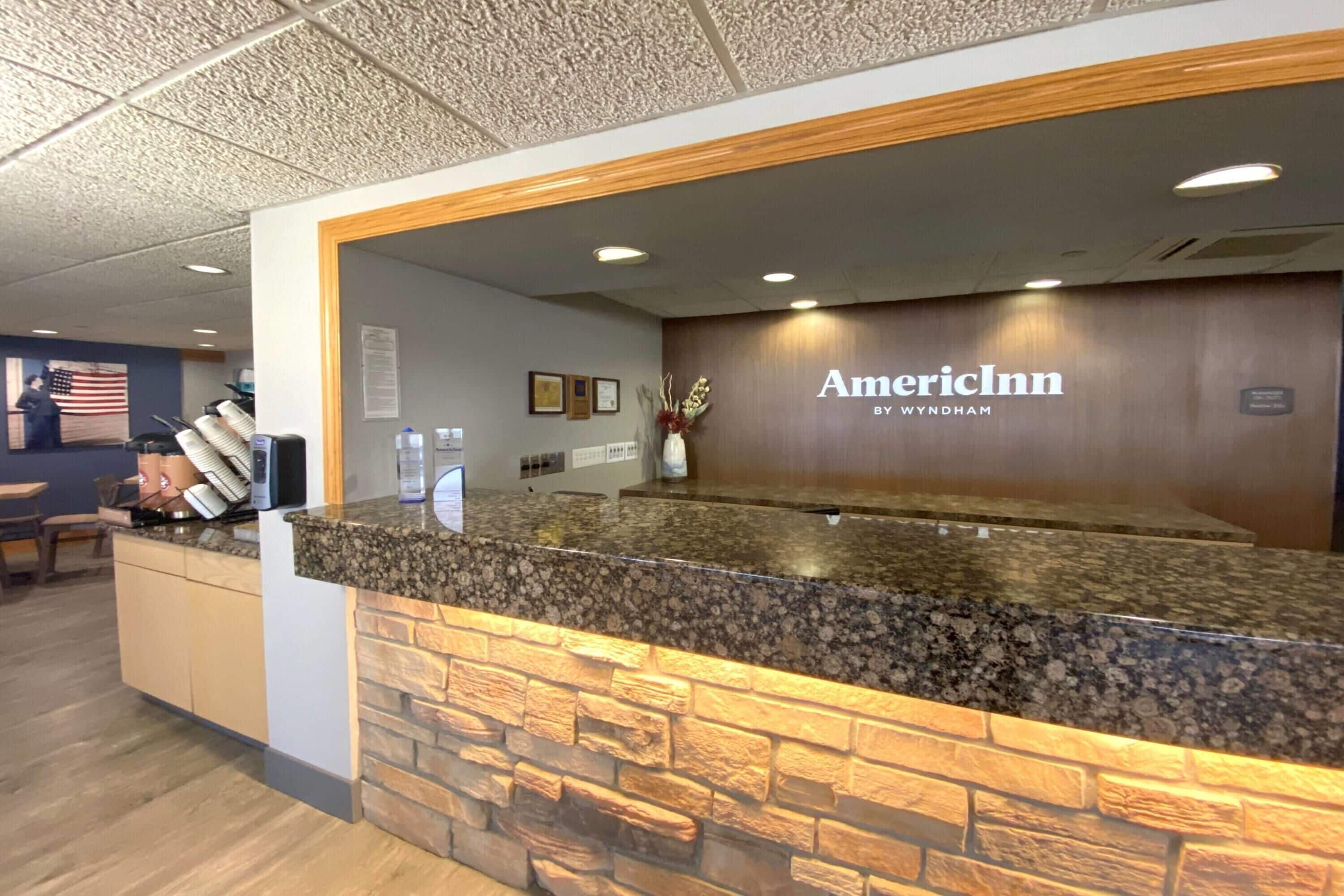 En receptionsdisk med en fasad av sten, en träram och logotypen för American Inn.
