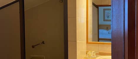 Un baño con ducha envuelta en vidrio, un lavabo y un espejo.