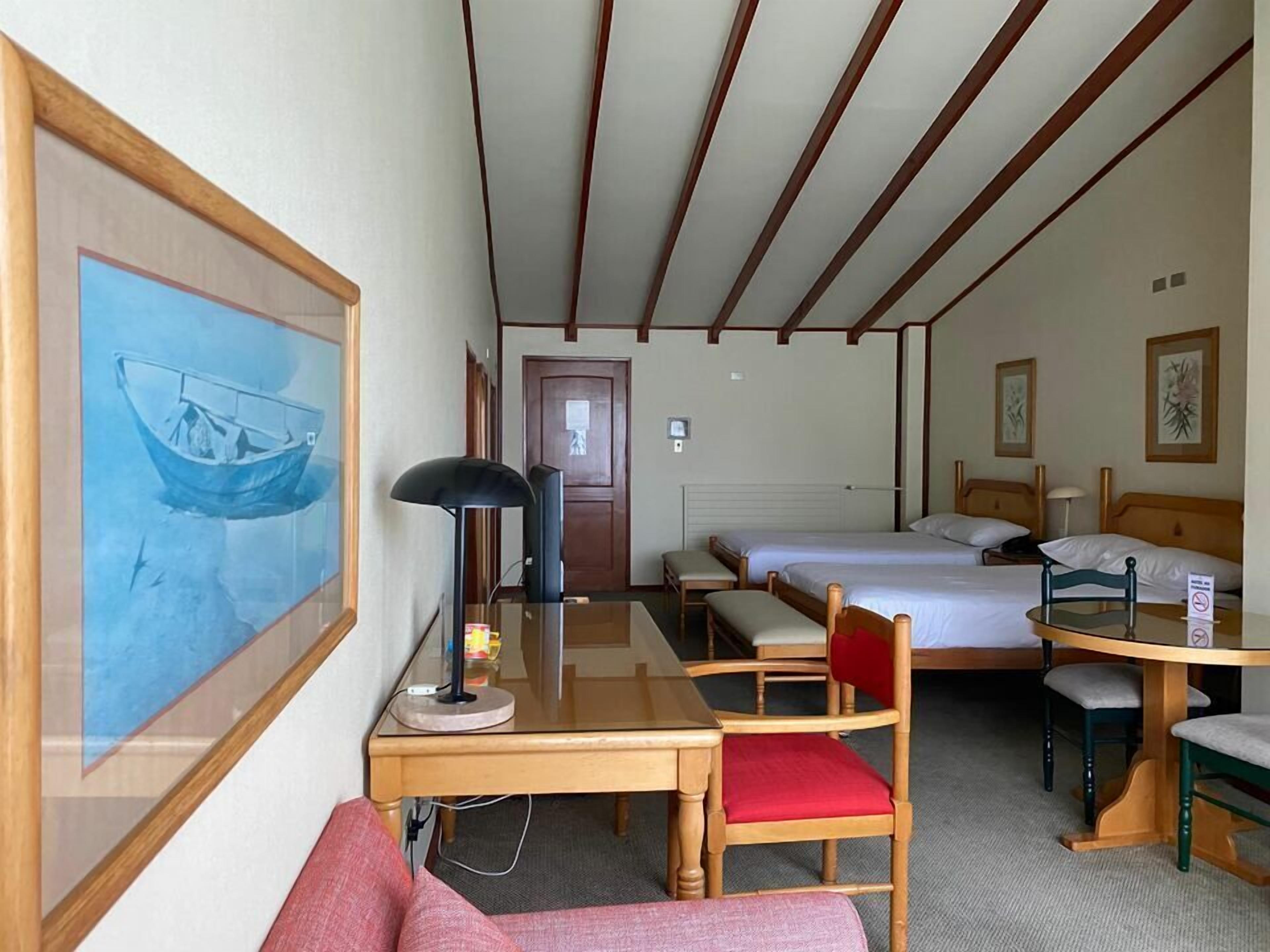 A hotel room with a bed, a desk with a chair, a table, and a couch.