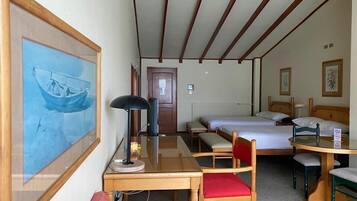 A hotel room with a bed, a desk with a chair, a table, and a couch.