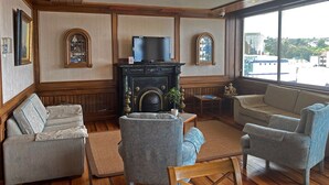 Una sala de estar con chimenea, dos sillones, un sofá y un televisor.