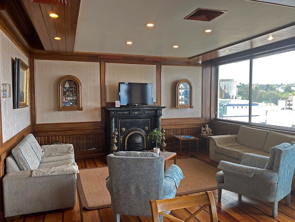 A living room with a fireplace, two armchairs, a sofa, and a television.