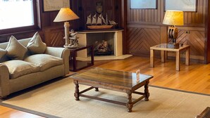 Una sala de estar acogedora con suelo de madera, una mesa de centro de vidrio, un sofá color beige y dos lámparas.