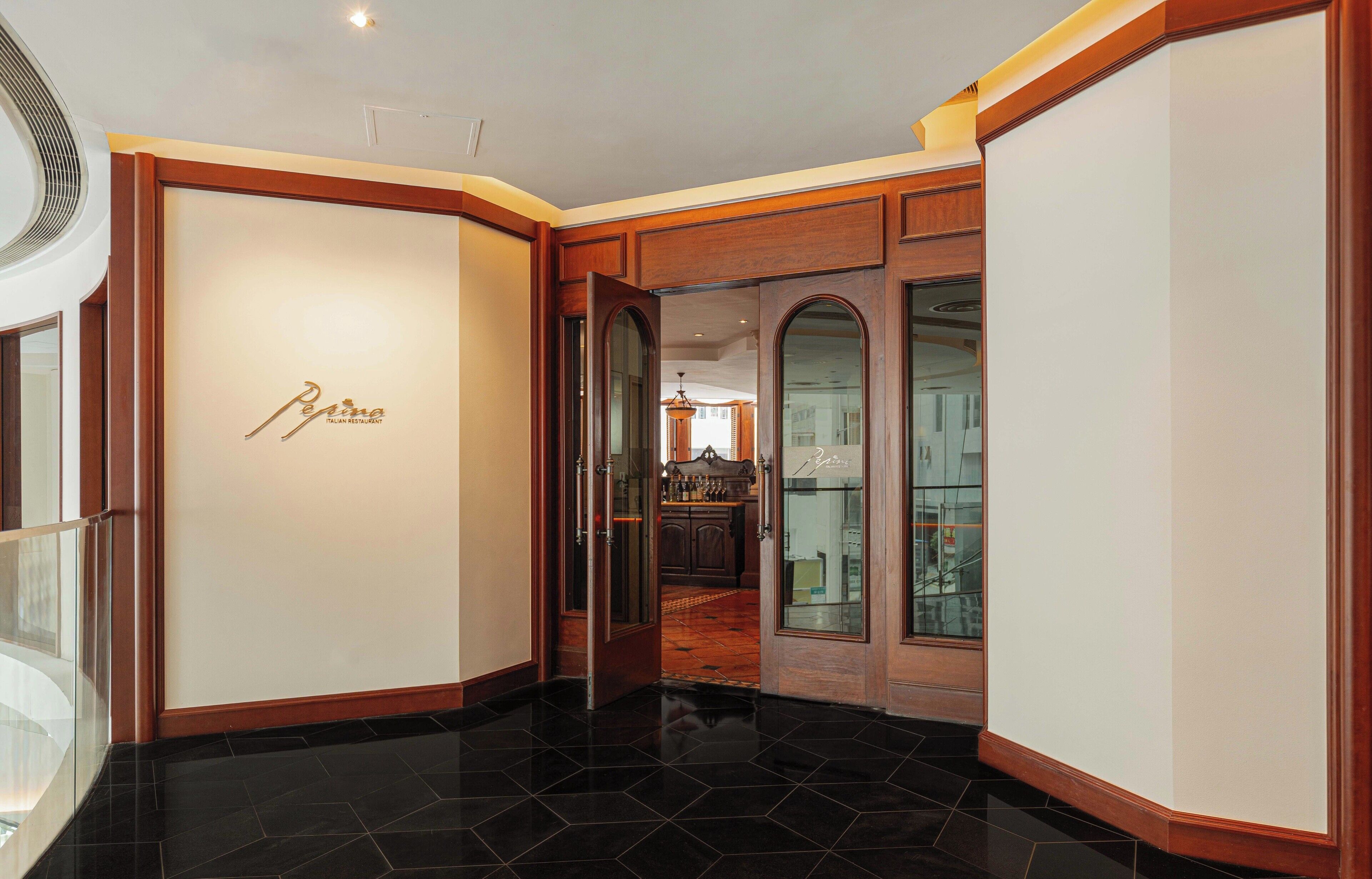 A polished lobby with a black-tiled floor, a reception desk, and a visible restaurant area in the background.