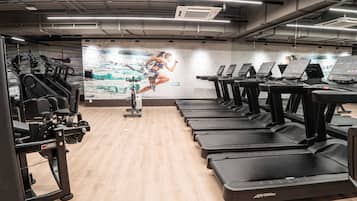 A gym with treadmills, weight machines, and a large mural of a runner.
