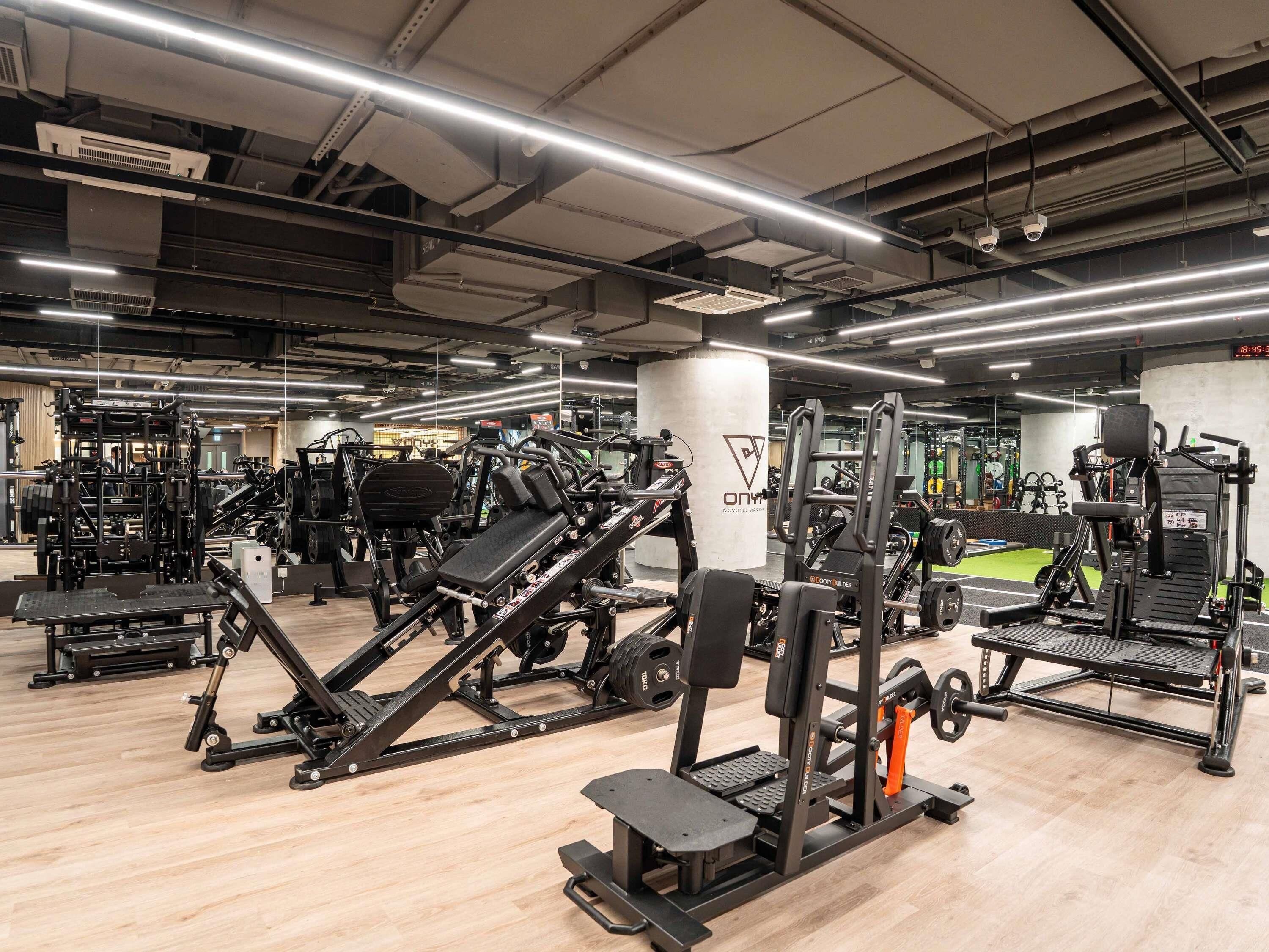 A gym with various exercise equipment, a mirrored wall, and a digital clock displaying 18:45.