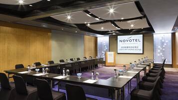 A conference room with a long table, chairs, and a presentation screen.