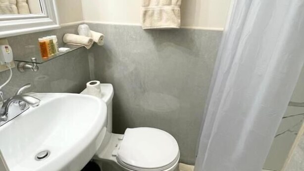 A bathroom with a sink, toilet, and towel rack. - Da Vinci Hotel (New York)