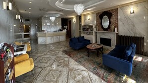A spacious lobby with a marble floor, a reception desk, blue sofas, a fireplace, and a chandelier. - Da Vinci Hotel (New York)