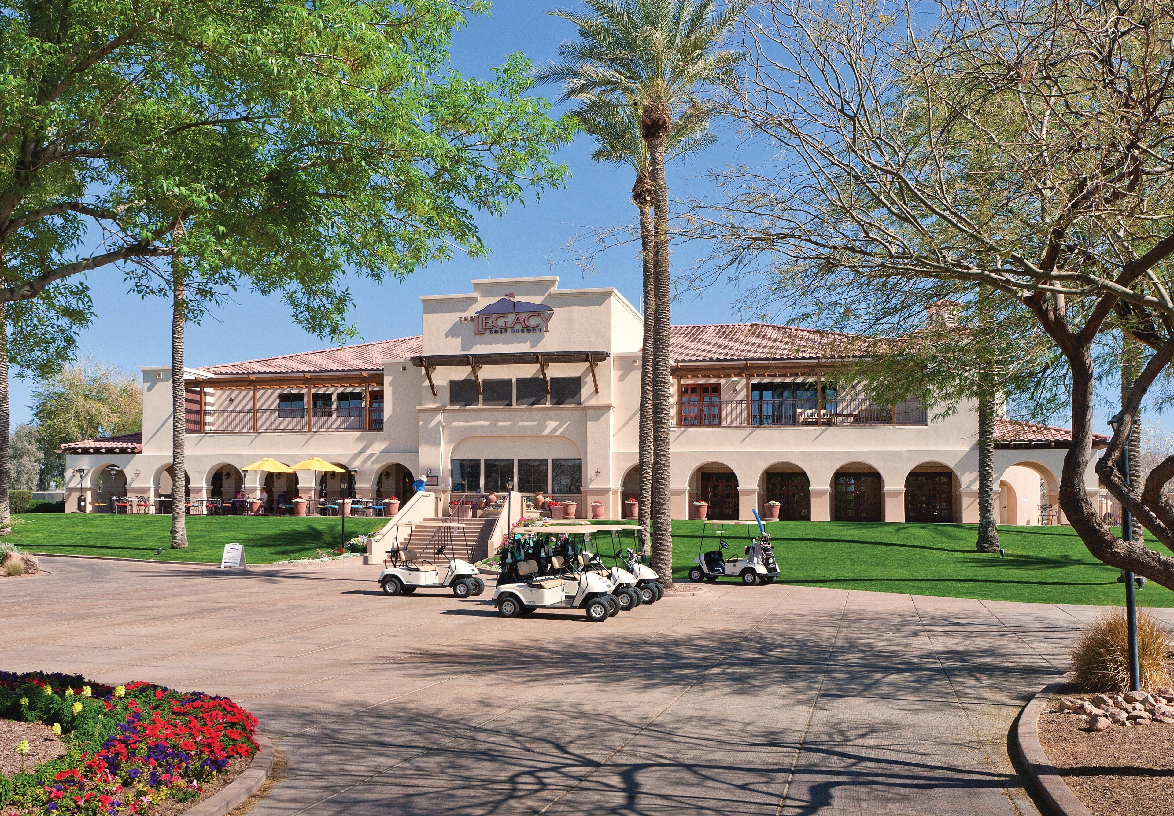 A building with a central entrance, multiple balconies, and a well-maintained lawn.
