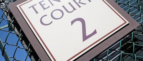 Une pancarte sur la clôture d’un terrain de tennis porte l’inscription « TERRAIN DE TENNIS N° 2 ».