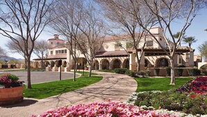 A building with a courtyard, a paved walkway, and flowering plants.