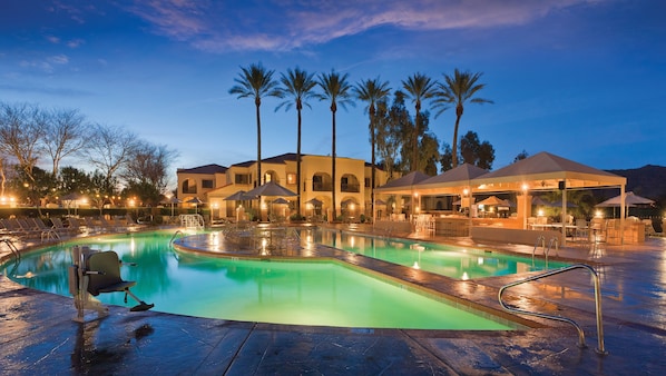 Una piscina al aire libre, sombrillas, sillones reclinables de piscina