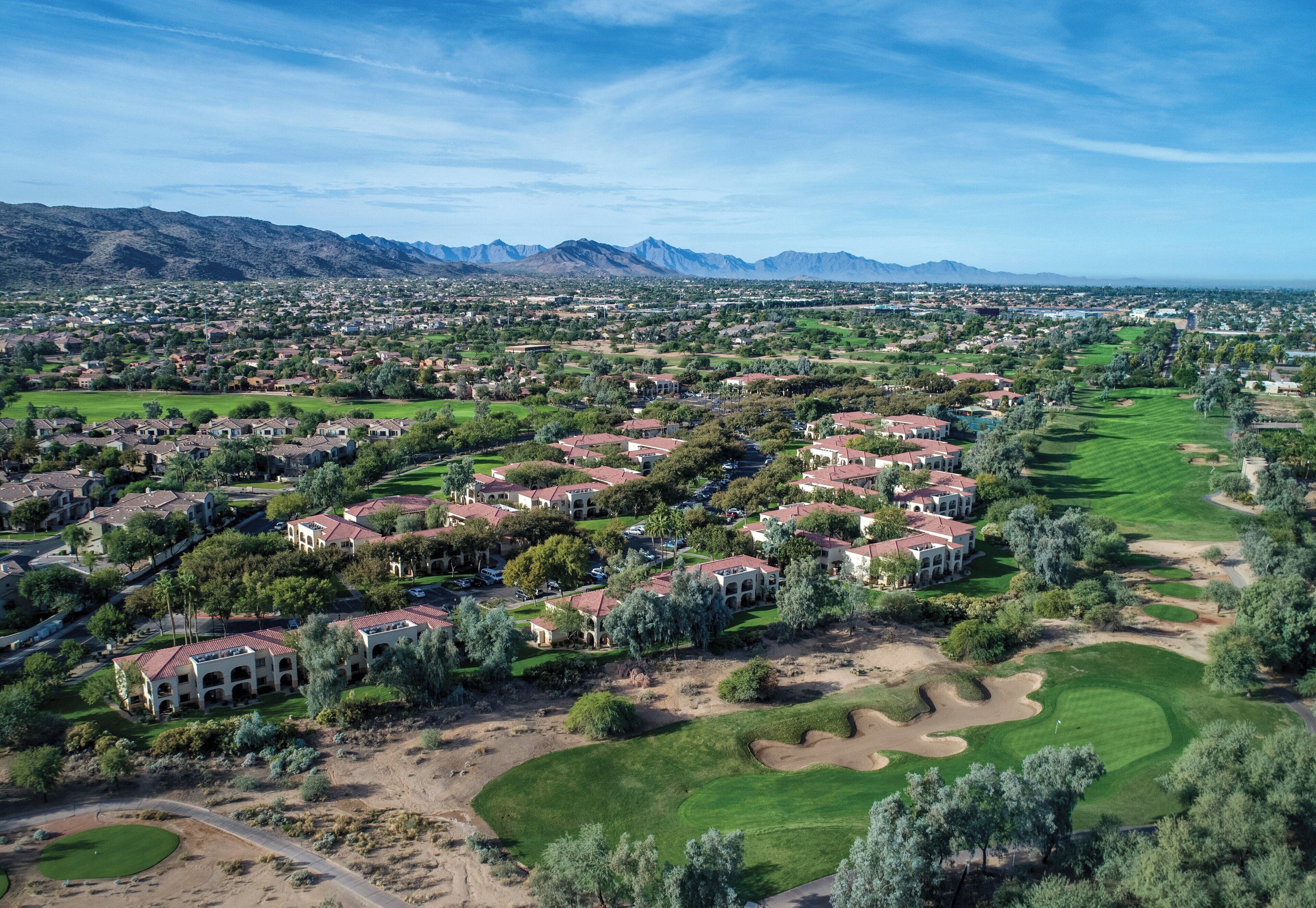 An aerial view of a residential area with houses, green spaces, and a golf course.