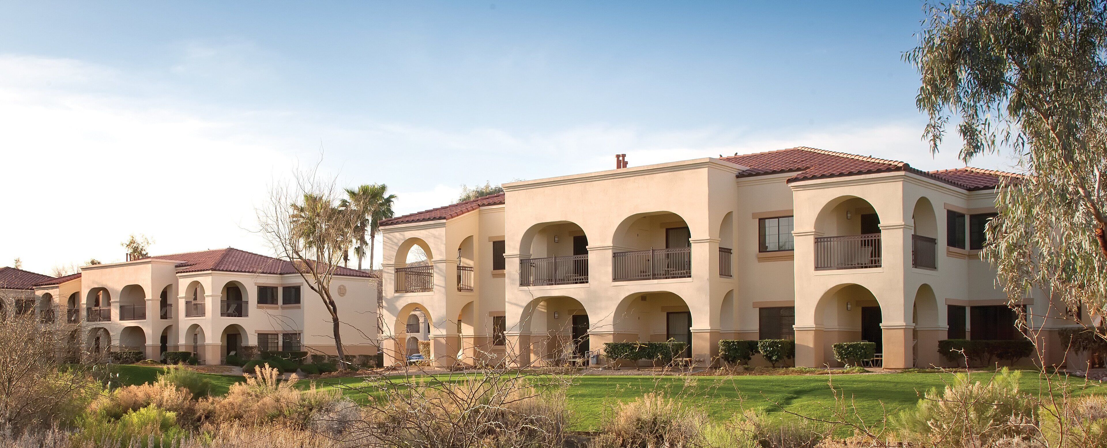A multi-story building with arched balconies and a red-tiled roof.