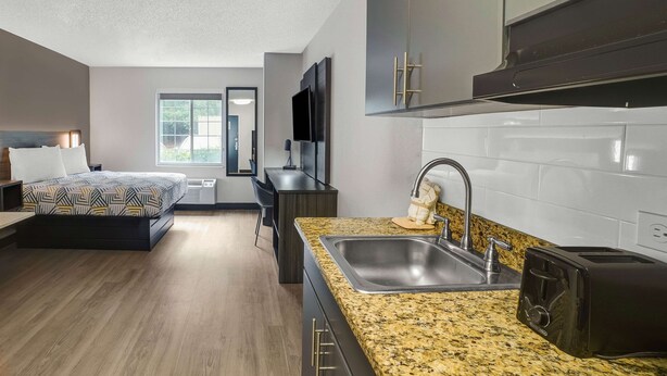 A modern kitchen with a granite countertop, stainless steel sink, and a black toaster.