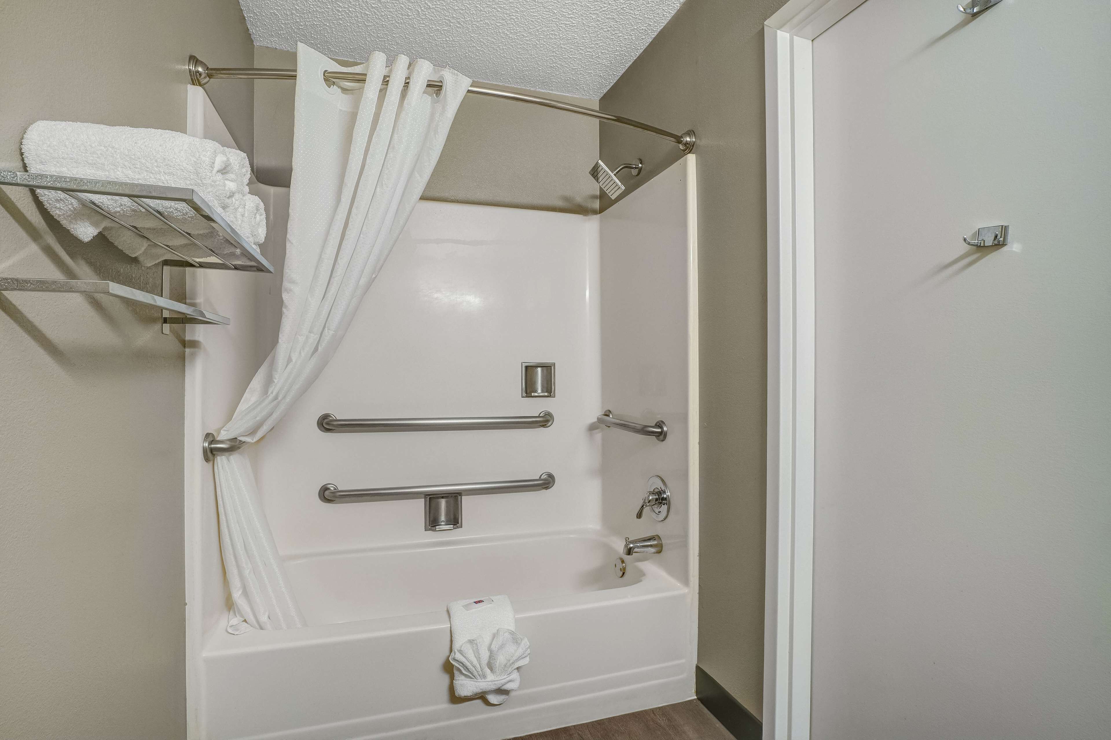 A modern bathroom with a walk-in shower, grab bars, and a towel rack.